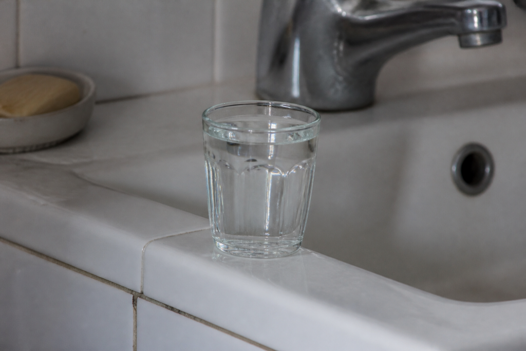 Gobelet transparent plein sur un lavabo blanc carrele