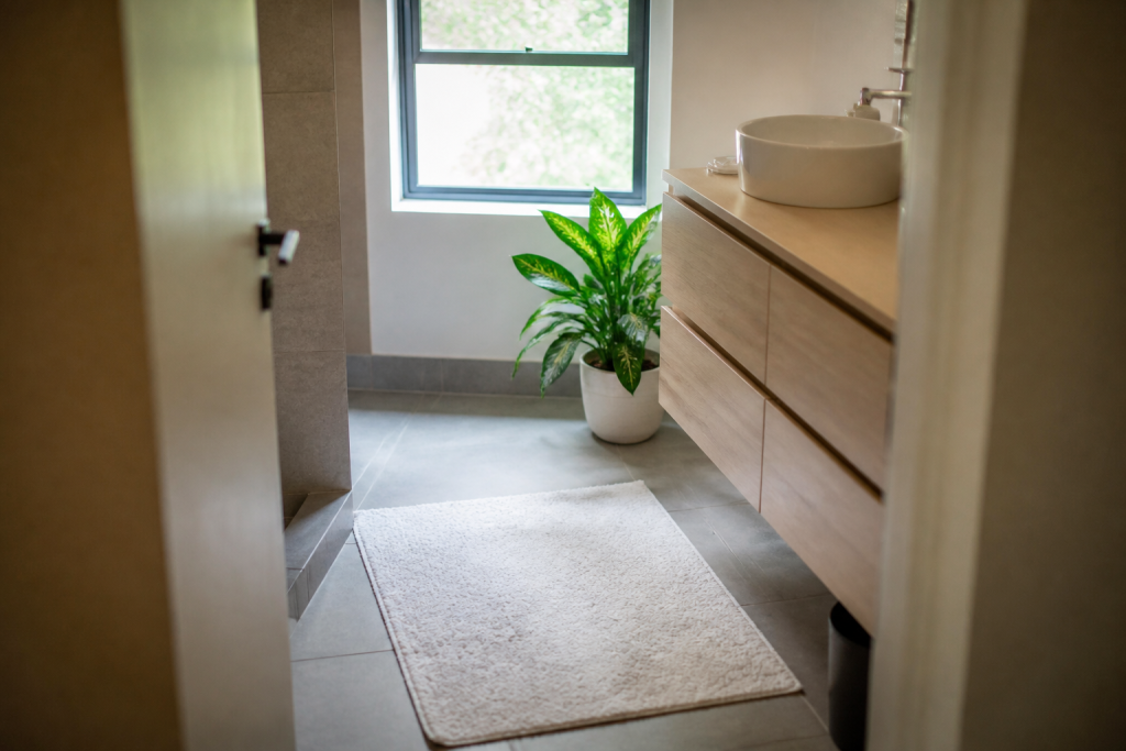 Salle de bain avec tapis blanc et plante verte