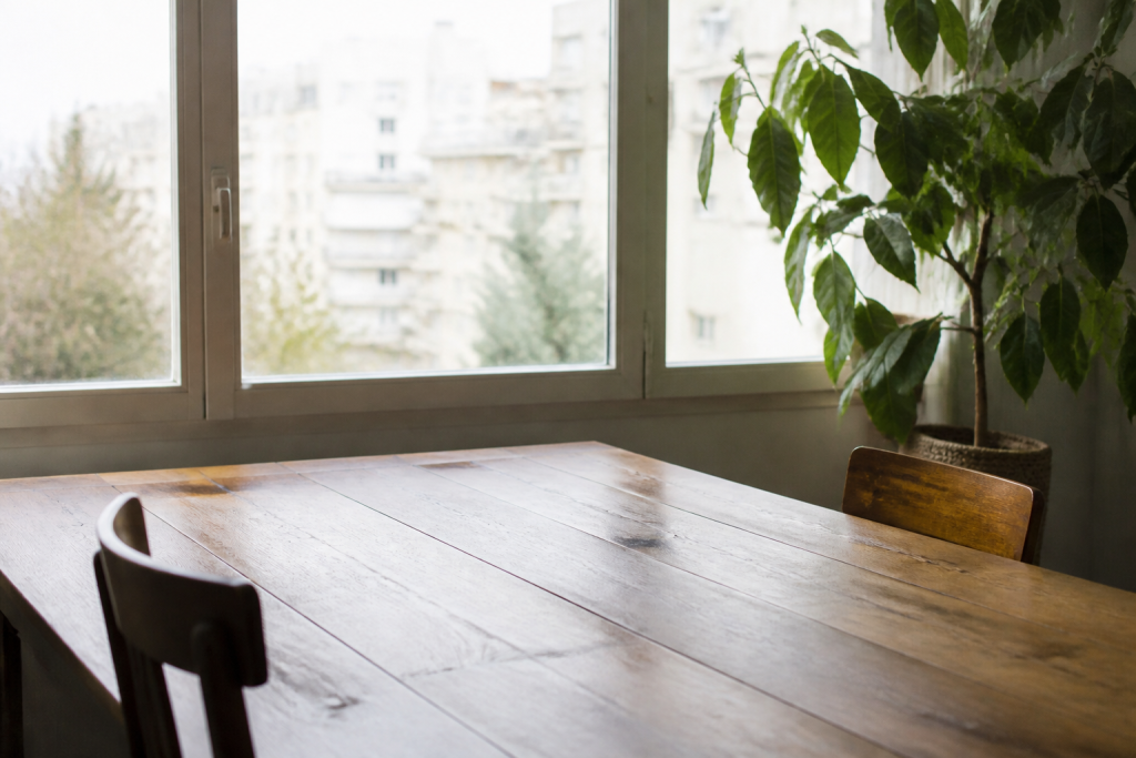 Table en bois devant grande fenetre avec plante verte